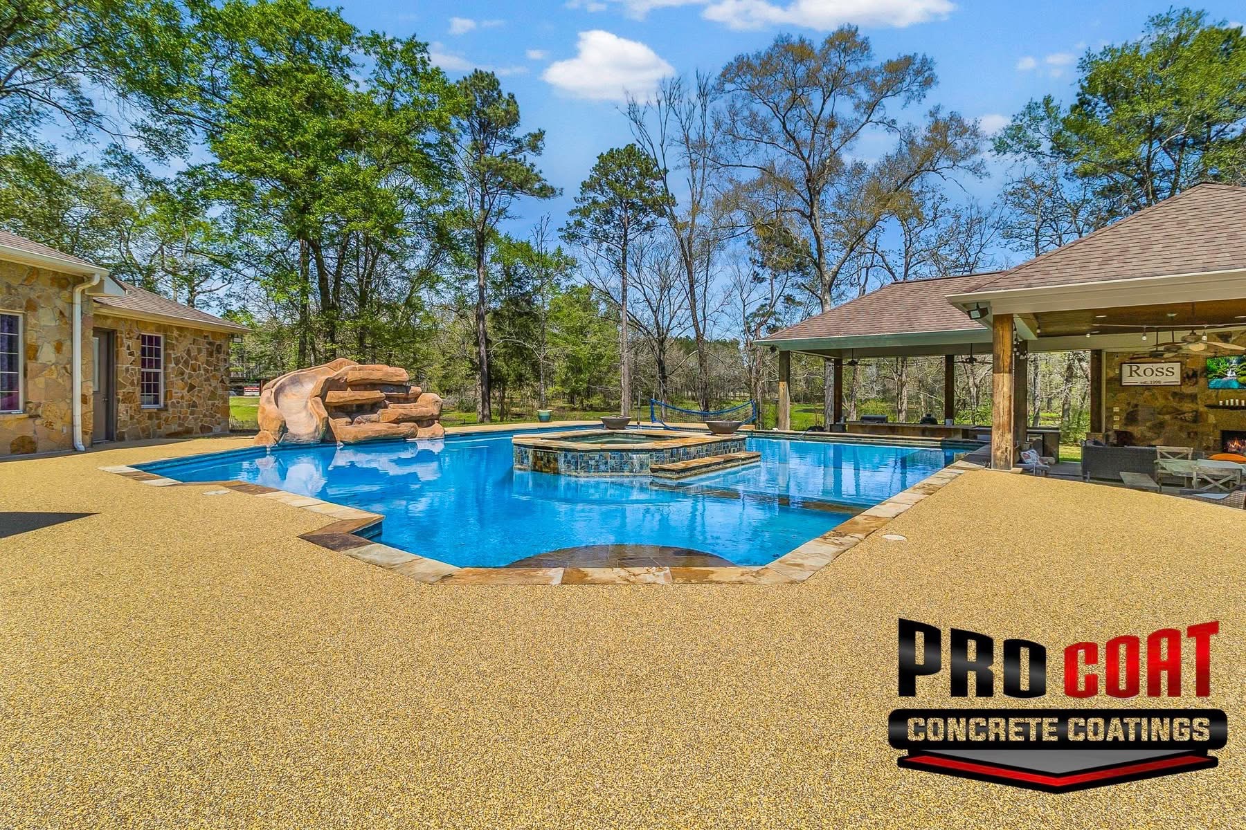 Tan speckled Pro-Flex deck surfacing around a freeform pool with a rock waterslide and spa