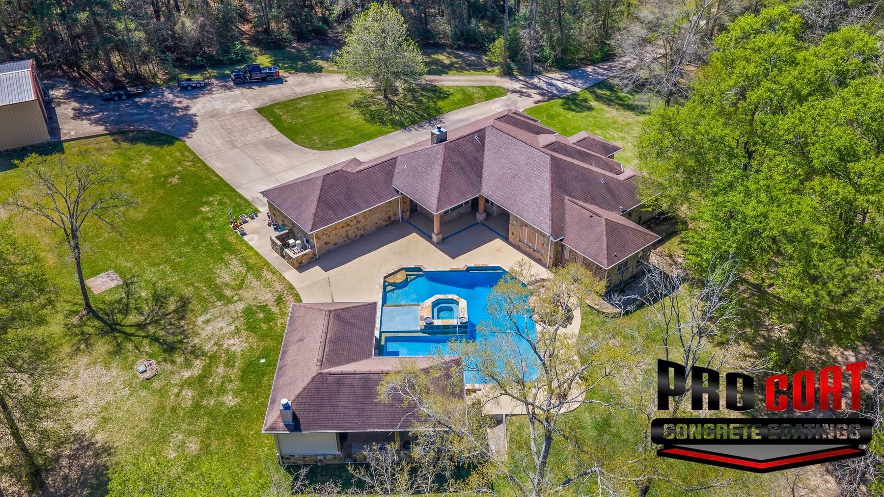 Aerial view of a home and pool finished with light blue speckled deck surfacing