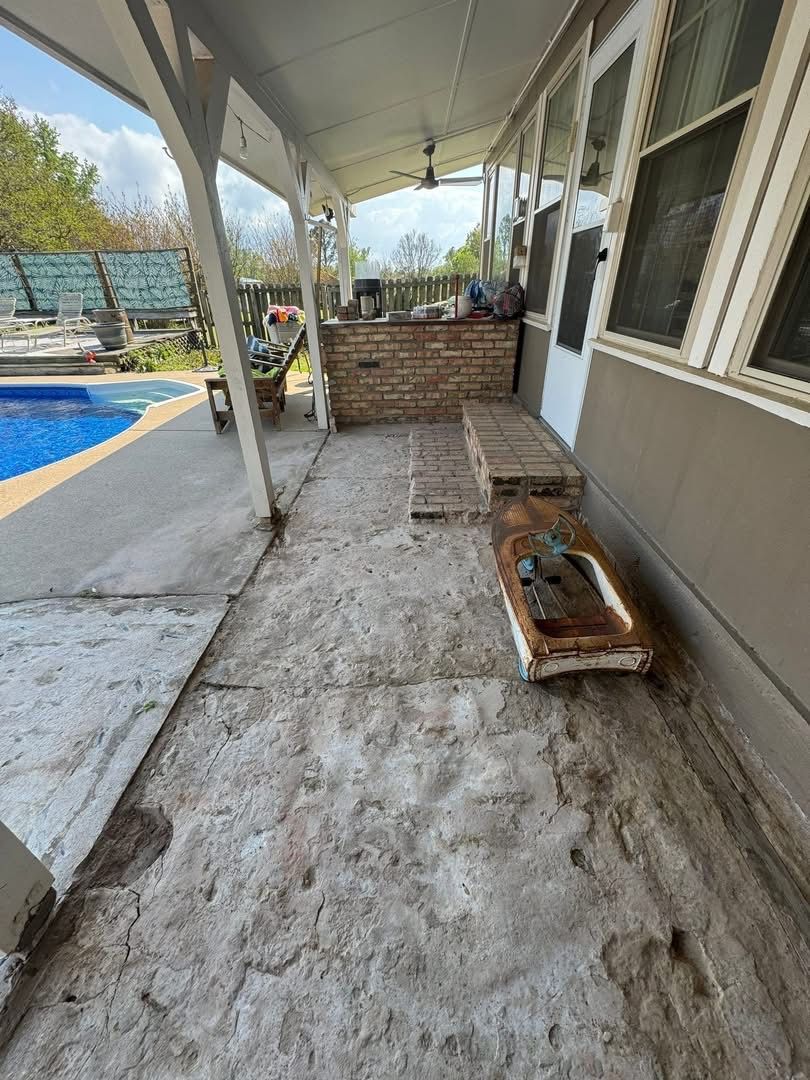 Bare gray concrete covered porch with a wooden bench before resurfacing