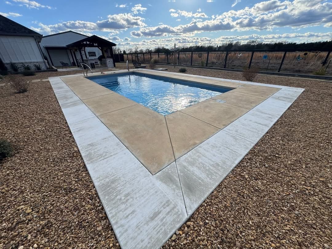 Light gray broom-finish concrete pad bordered by pea gravel before resurfacing