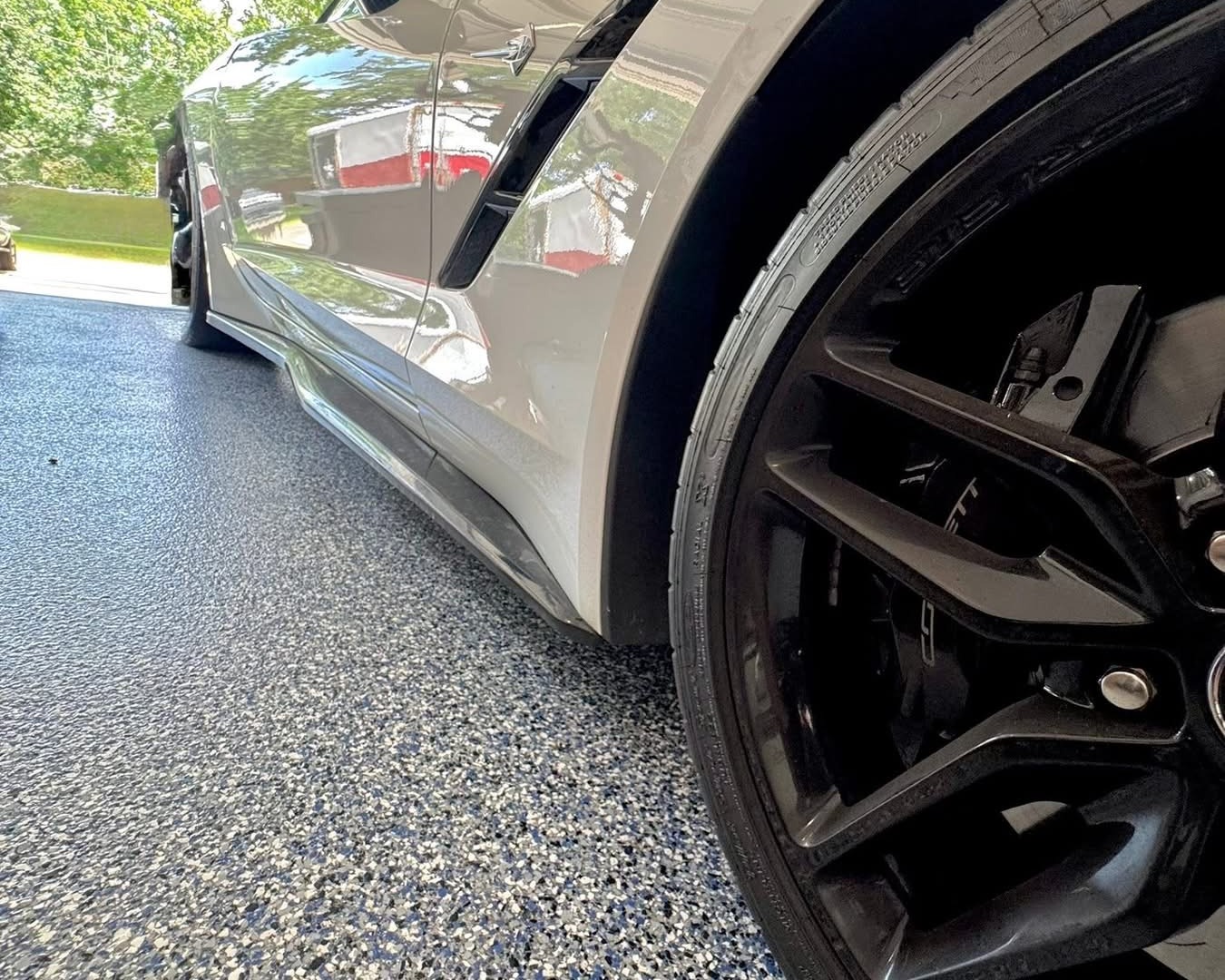 Blue and gray polyaspartic flake floor coating in a garage beside a sports car
