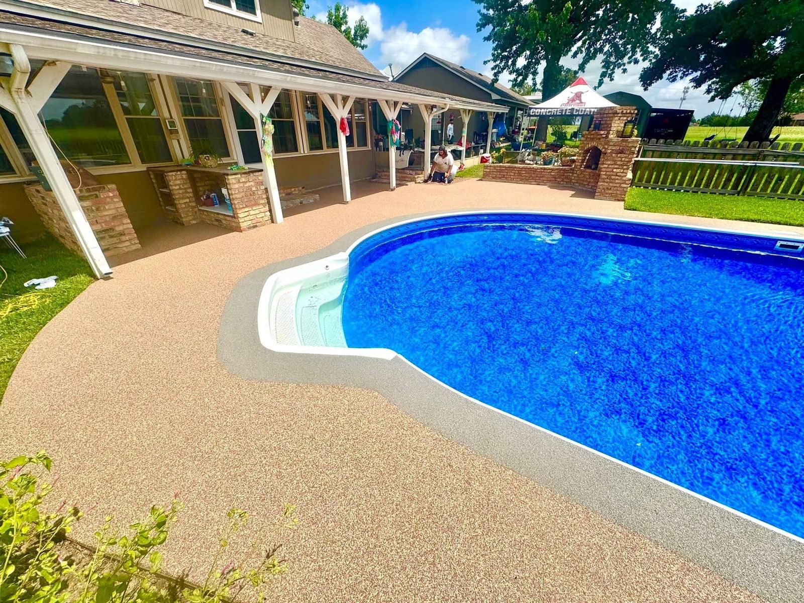Stamped stone-pattern deck with planters and built-in bench seating around a pool