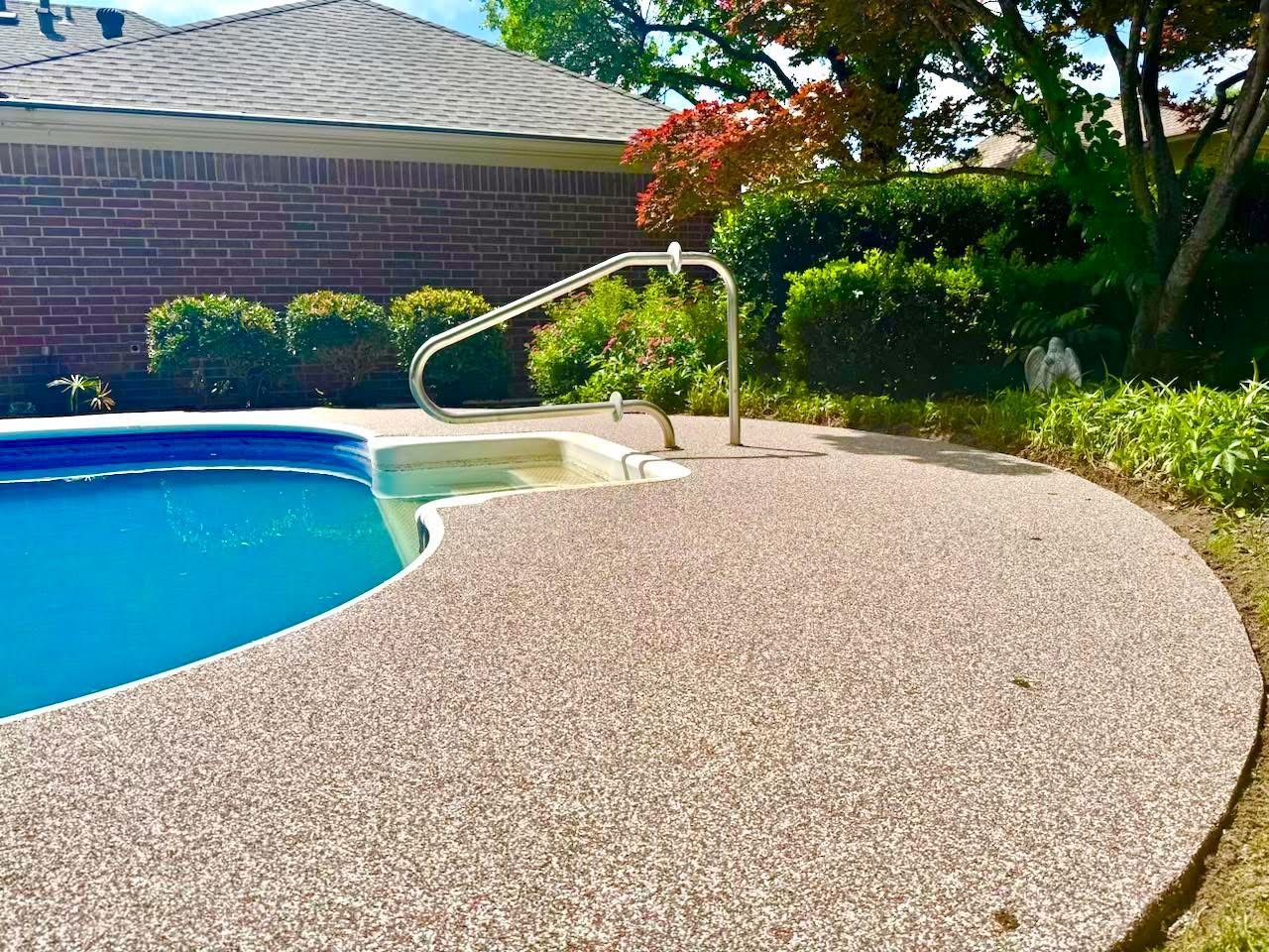 Curved pool deck in tan speckled coating with a wrought iron handrail