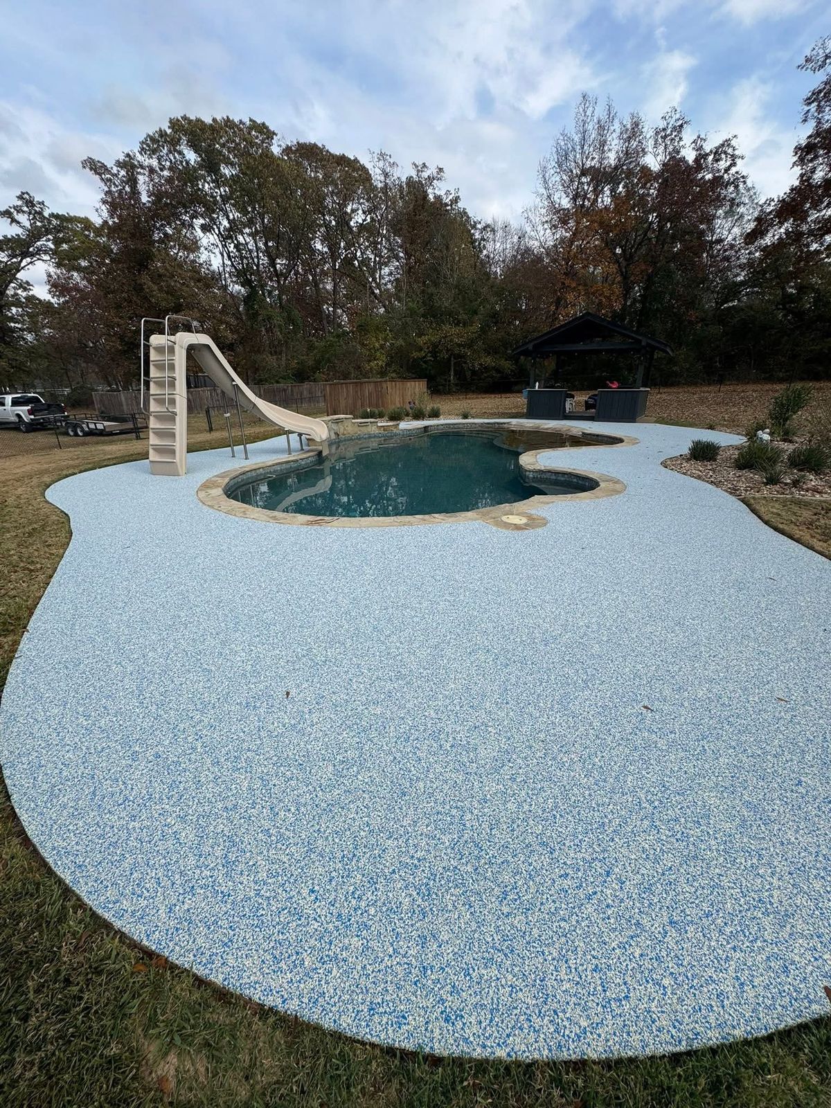 Aerial view of a freeform pool with a water slide finished in light blue speckled coating