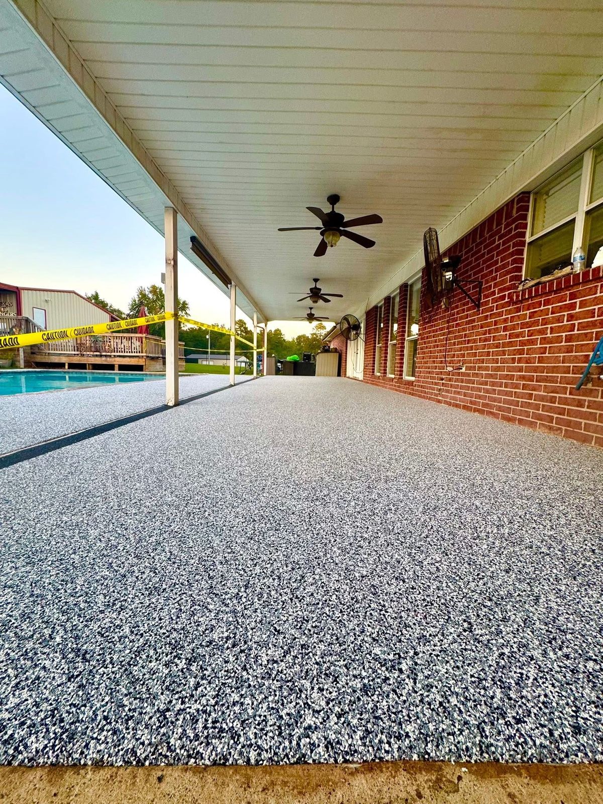 Blue-gray speckled deck on a covered porch beside a brick home