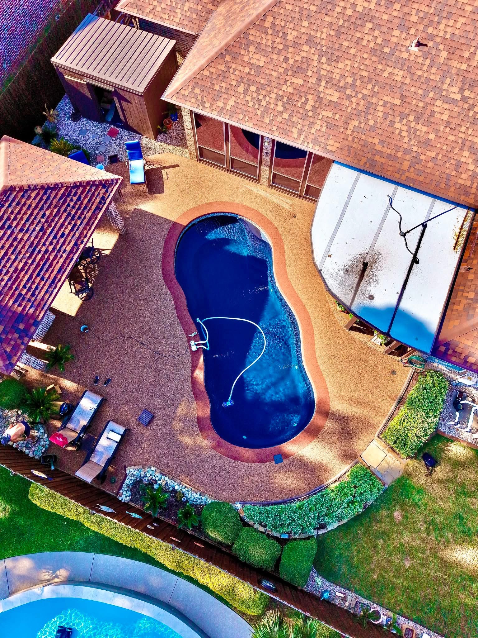 Aerial view of a kidney pool with tan speckled Pro-Flex deck surfacing