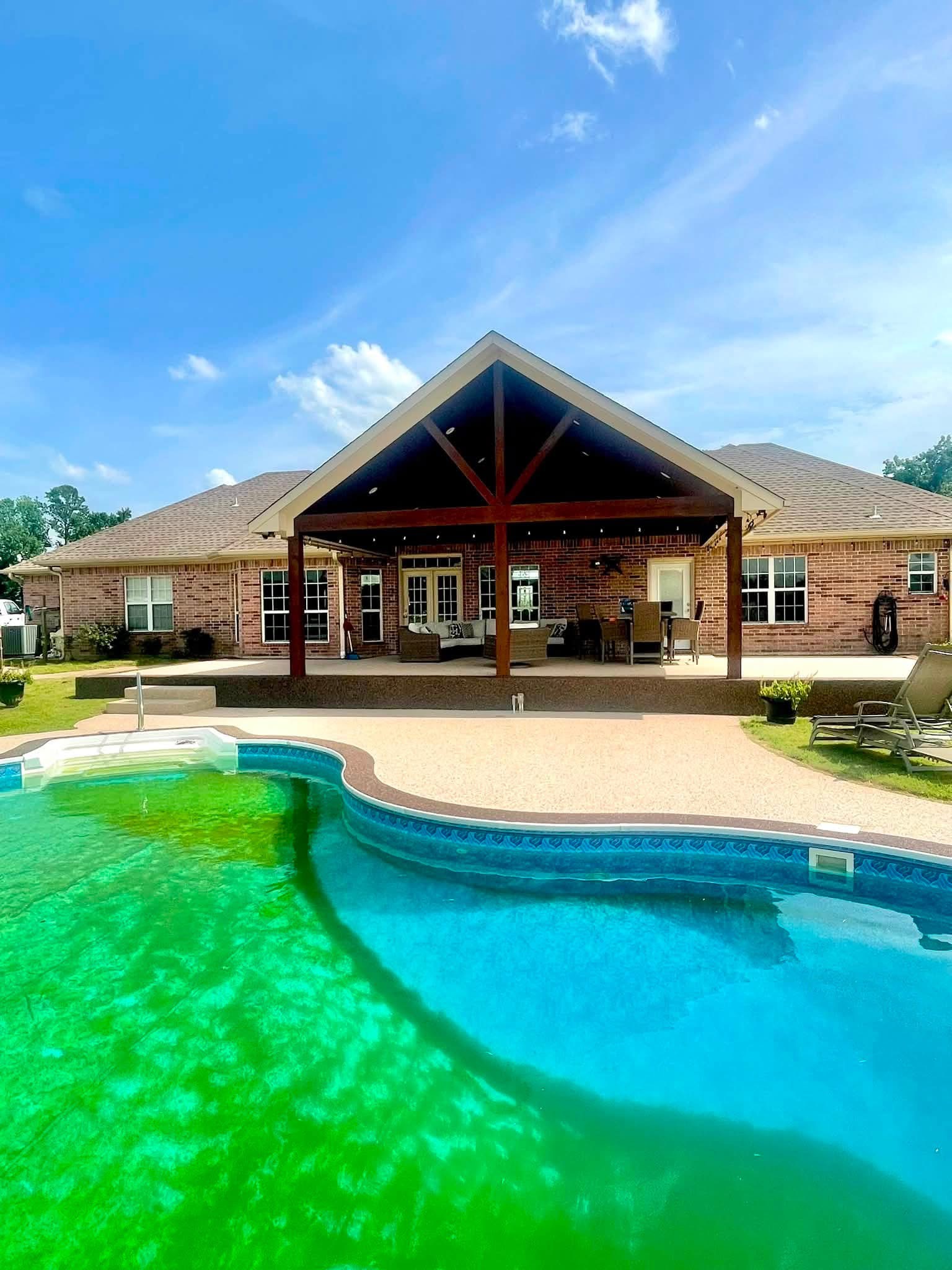 Kidney pool with tan speckled Pro-Flex deck under a covered gable patio