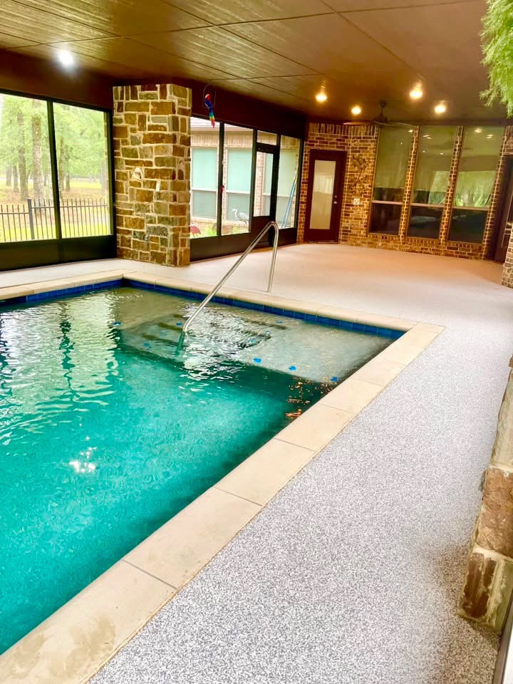 Screened-in indoor pool with light gray speckled Pro-Flex deck surfacing and stone columns