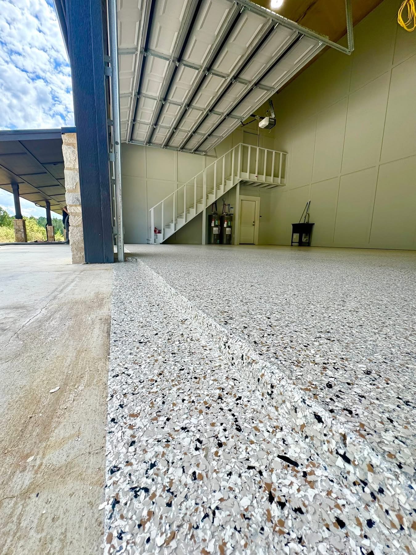 Large open garage bay finished with a tan and black speckled flake floor coating