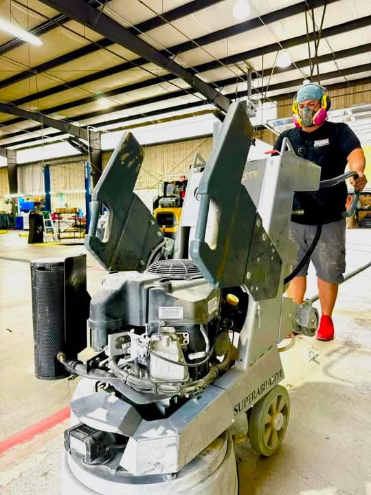 Professional diamond grinding equipment preparing a concrete floor for flake coating