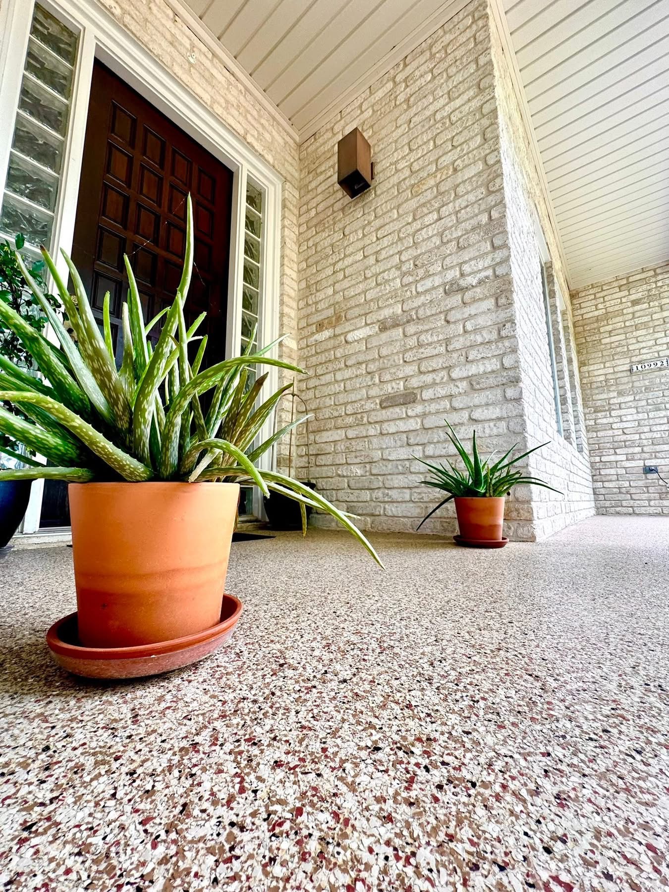 Covered patio with potted plants finished in a cream and tan speckled flake floor coating