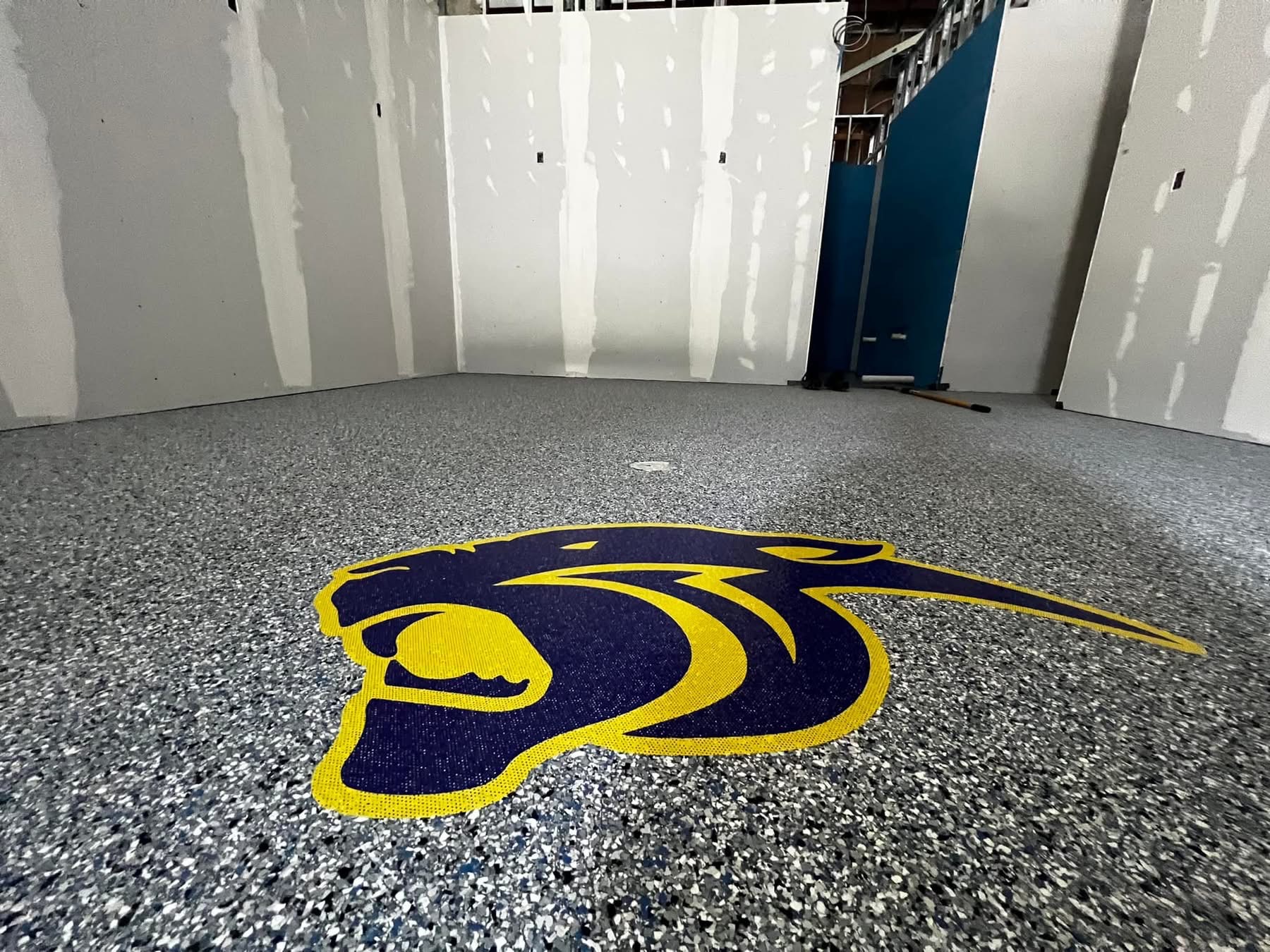 Commercial floor finished with a speckled flake coating and a custom mascot logo inlay