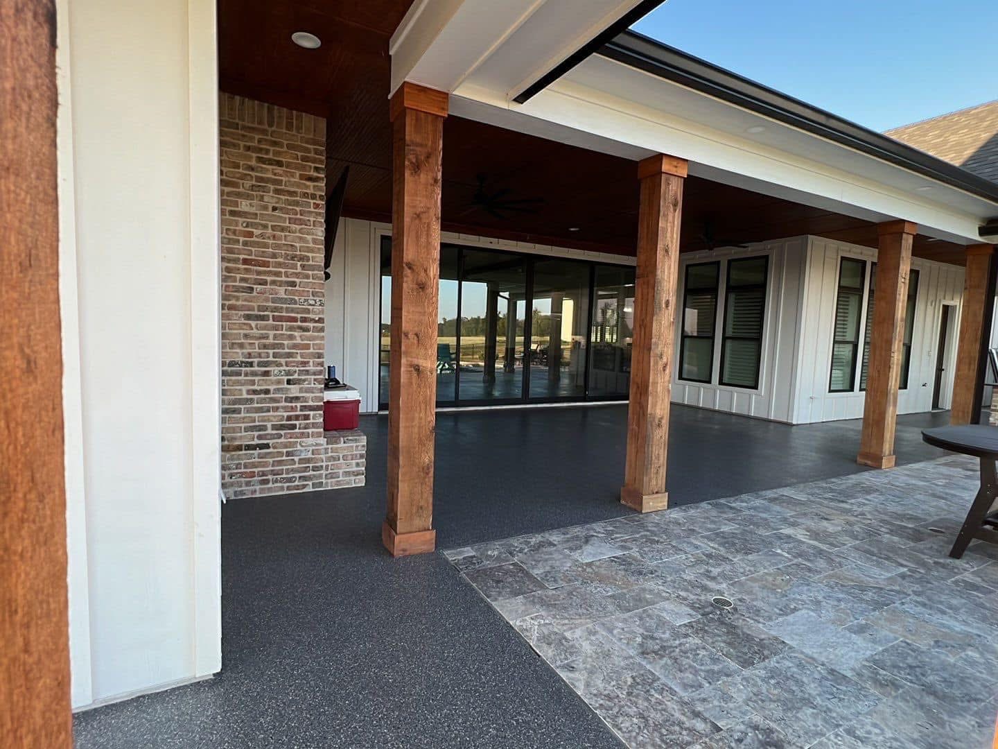Covered patio corner with a wood beam finished in a gray speckled flake floor coating
